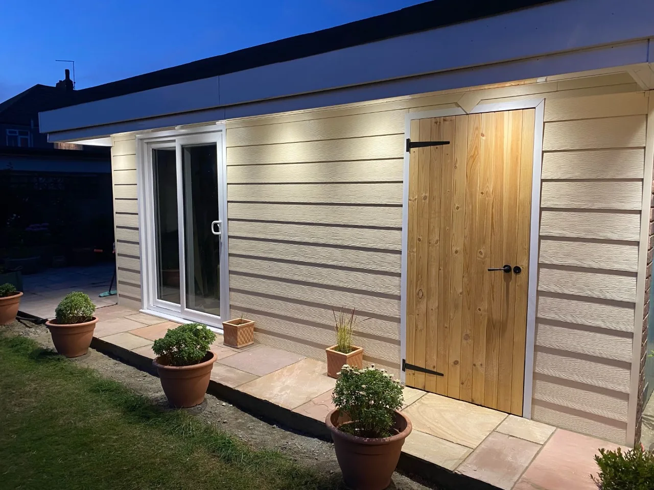 Garden room with broad horizontal embossed Fortex-style cladding and a timber door